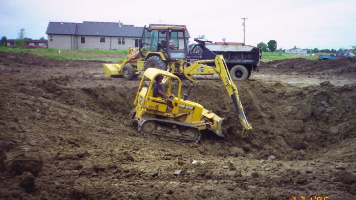 Brick Paver Construction excavator operators digging out dirt in the ground for a pond