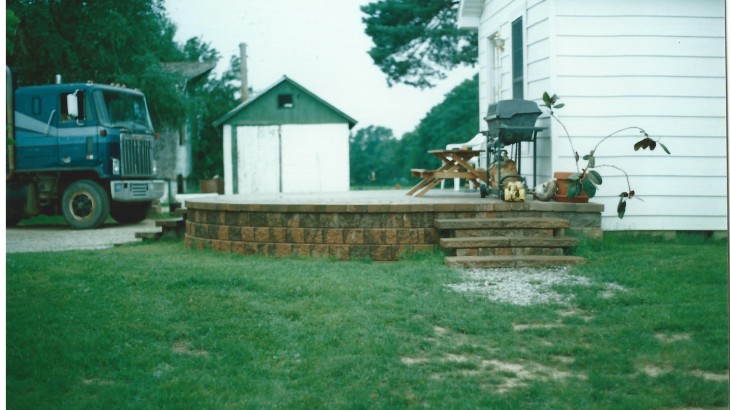 Brick stairs leading up to a brick pato with stove and bench
