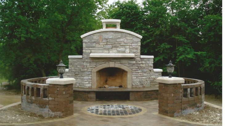 A custom made outdoor brick fireplace with a woodland backdrop
