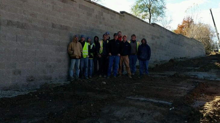 Brick Pavers Constrution team standing next to a brick wall in a recently excavated area