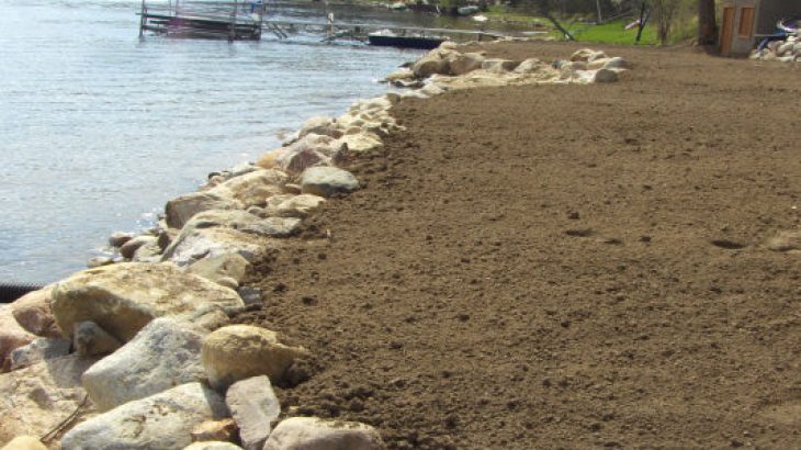 An excavated area by a lake brotected by a Boulder Sea Wall placed by Brick Paver Construction