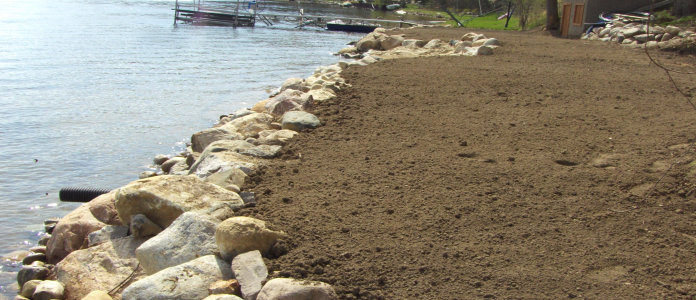 An excavated area by a lake brotected by a Boulder Sea Wall placed by Brick Paver Construction