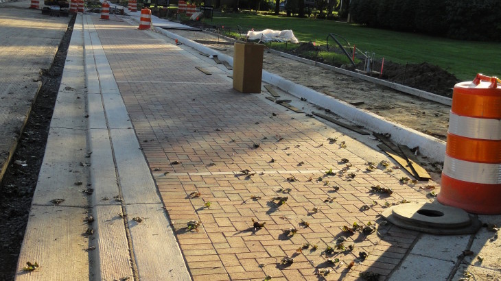 A brick pathway in a suburban area with construction and excavation taking place next to the path