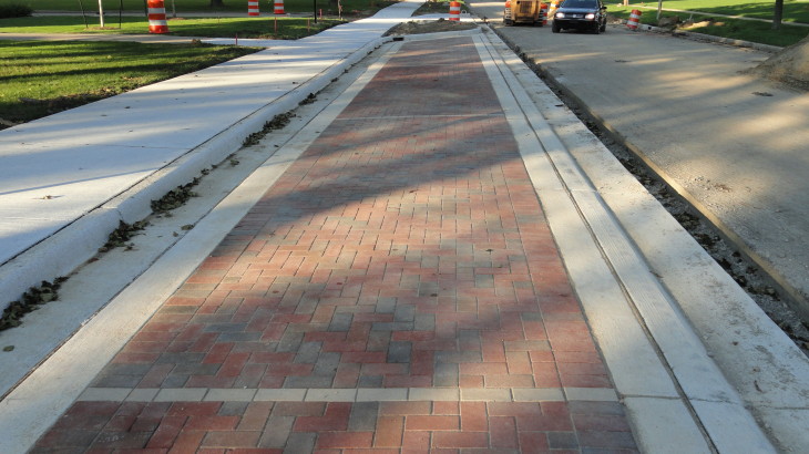 A brick pathway in a suburban area with excavation and construction happening in the streets
