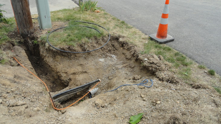 A hole dug by Brick Pavers Construction showing the plumbing and electrical wires by the street