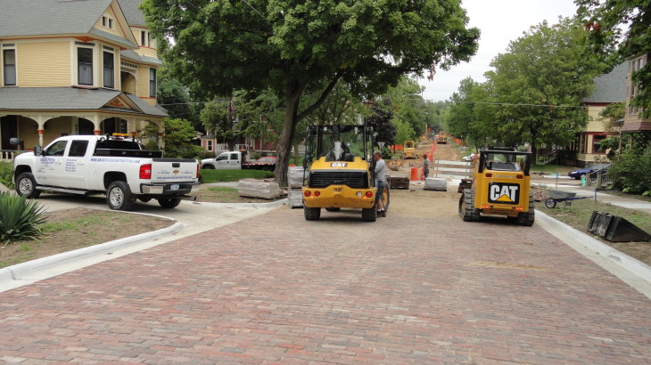 Two Cat excavators building a brick road in a suburban area