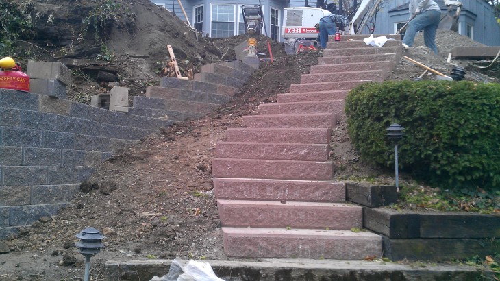 Brick stairs leading up to a house with a retaining wall on th eleft side of the house