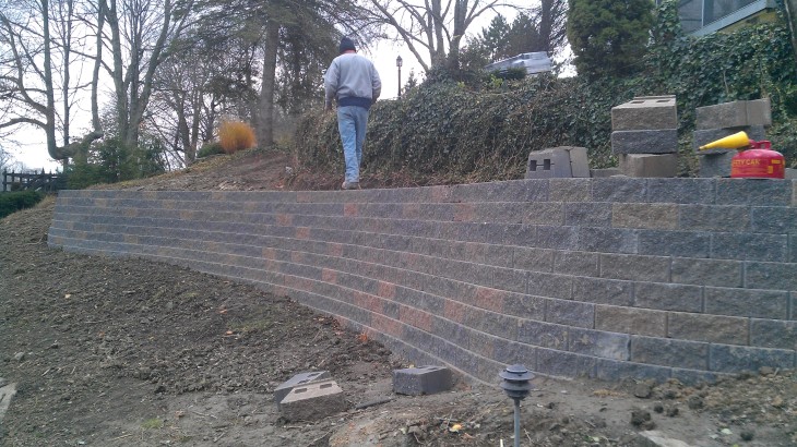 Brick Paver Construction worker standing on top of a brick retaining wall getting ready to finish up the details