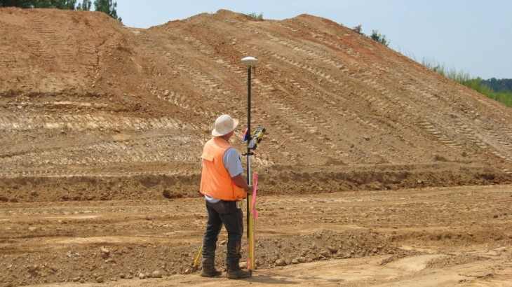 A man using excavation tools standing next to a mound of dirt