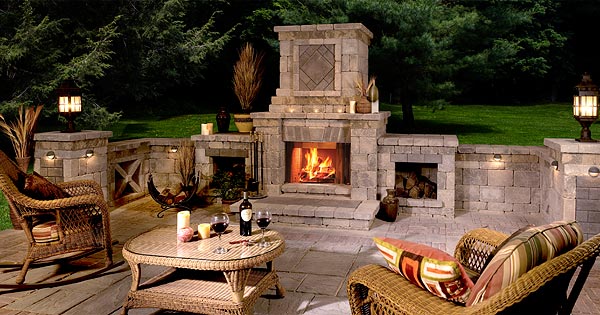 A stylized outdoor fireplace with chairs statoined around ready to enjoy the night