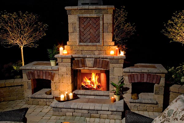 An outdoor sylized fireplace with a lit fire and candles