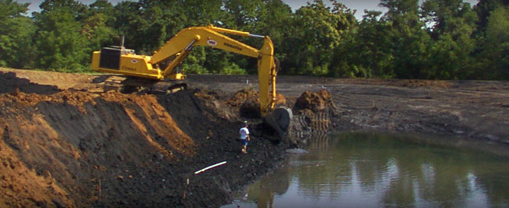 Brick Paver Construction digging out a man made lake in a wooded area
